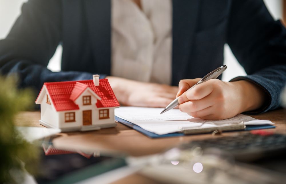 Property agent reviewing and signing purchase documents at a desk